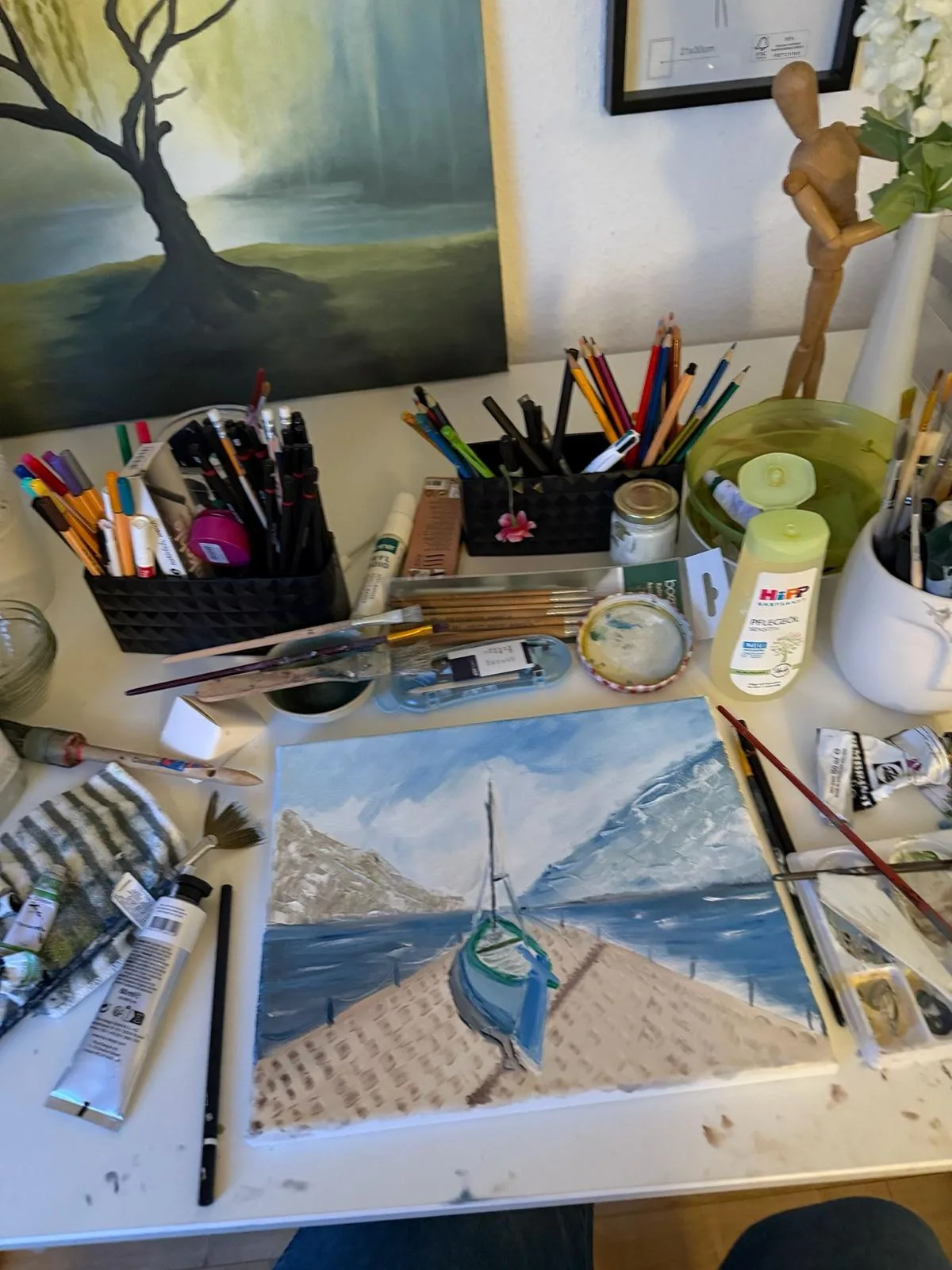 Arbeitstisch im Atelier mit Pinseln, Farben und Gemälden