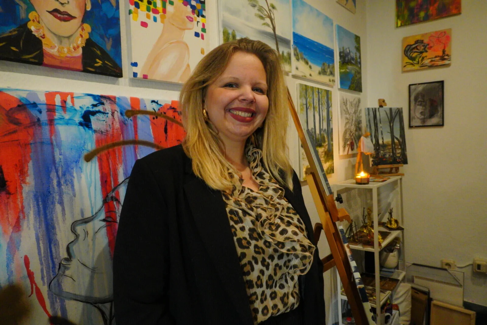 Christina Finch lächelnd in ihrem Atelier vor eigenen Werken